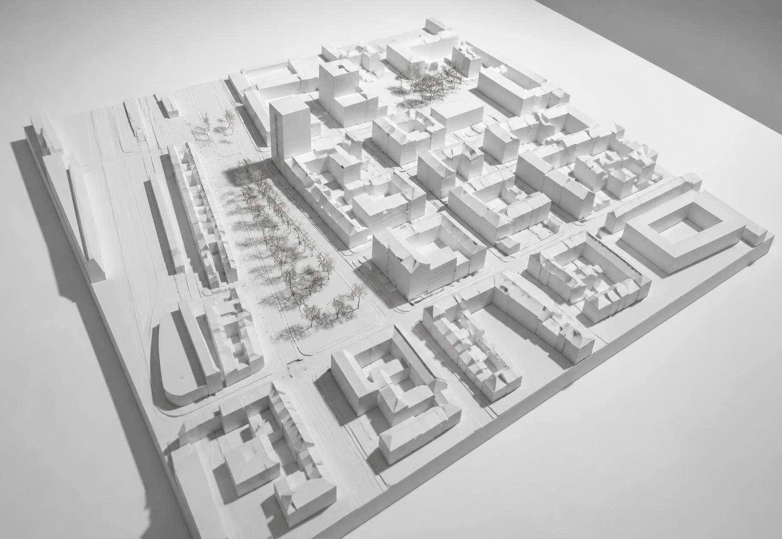White architectural scale model of an urban district showing streets, blocks and massing